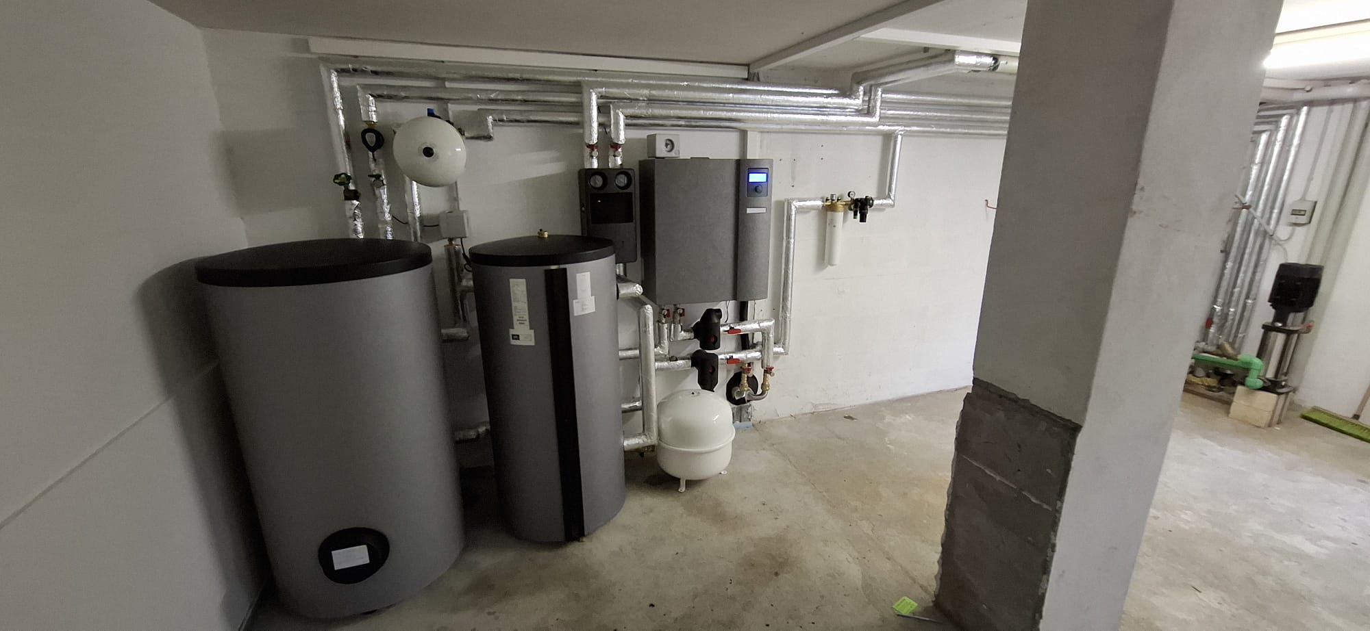 Wärmepumpen-Innenaufbau mit Pufferspeicher, Warmwasserspeicher und Regeltechnik in einem modern ausgestatteten Technikraum.